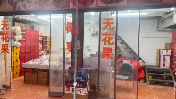 Guangzhou dried fruit stall with boxed figs, dates, and bulk carton stock displayed behind glass